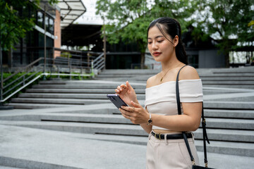Asian woman in a trendy outfit replying to a chat or using a mobile app.