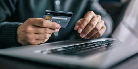 Hands holding plastic credit card and using laptop