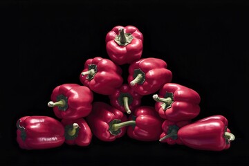 group red bell peppers in the corner isolated on black