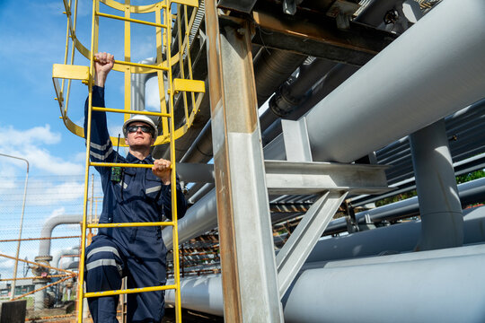 Front view of factory engineer or technician worker climb up on stair of  petrochemical gas pipeline to work or maintenance in workplace.