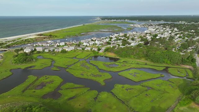 Expansive view of lush green marshland, Atlantic ocean in Cape Cod, idyllic charming homes, aerial panoramic