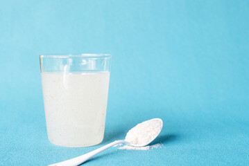 A glass of water soluble psyllium husk dietary fiber supplement on light aqua  background.
