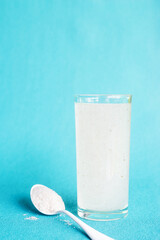 A glass of water soluble psyllium husk dietary fiber supplement on light aqua  background.