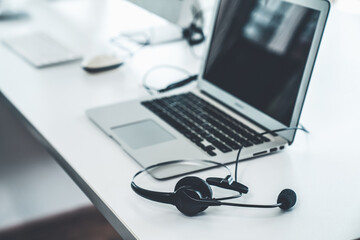 Fototapeta premium Efficient Remote Workstation Setup: Laptop and Headset on Minimalist Desk for Seamless Communication and Productivity in a Home Office or Call Center Environment
