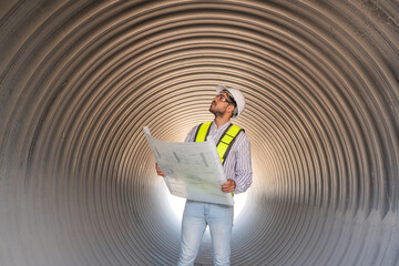 Young mechanical engineer holding blueprint drawing to checking and inspection pipeline system new...