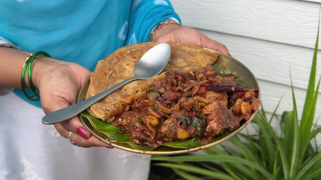 A girl holding a plate of Sukha mutton and paratha made with coconut oil. No face video