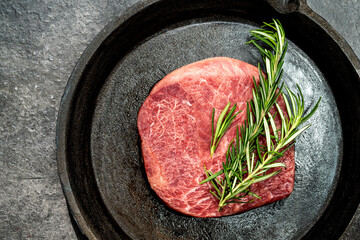 A piece of tenderloin meat is on a pan with some herbs on top