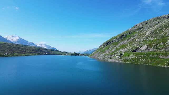 A stunning drone view over the Spl&uuml;gen Pass, capturing crystal-clear alpine lakes surrounded by towering mountains. The serene landscape showcases nature's beauty at the border of Switzerland Italy