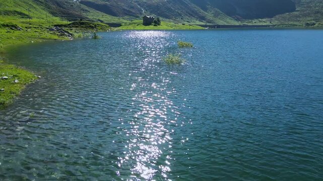 A stunning drone view over the Spl&uuml;gen Pass, capturing crystal-clear alpine lakes surrounded by towering mountains. The serene landscape showcases nature's beauty at the border of Switzerland Italy