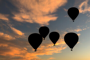 Hot air balloons in dark blue, red and yellow colors flying in a slightly cloudy blue sky