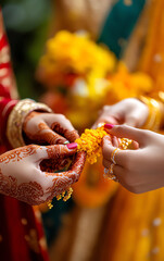 Close-up of hands adorned with intricate henna designs exchanging vibrant flower garlands during a traditional celebration.
