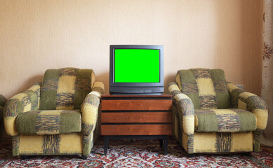 Antique TV with green screen on an antique wooden cabinet, old design in a house in the style of...