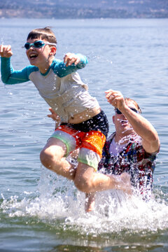 Father lifting son in the air while playing in water at the beach
