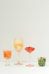 Assorted colorful candies and olives displayed in elegant glassware.