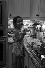 Toddler girl having fun cooking in the kitchen