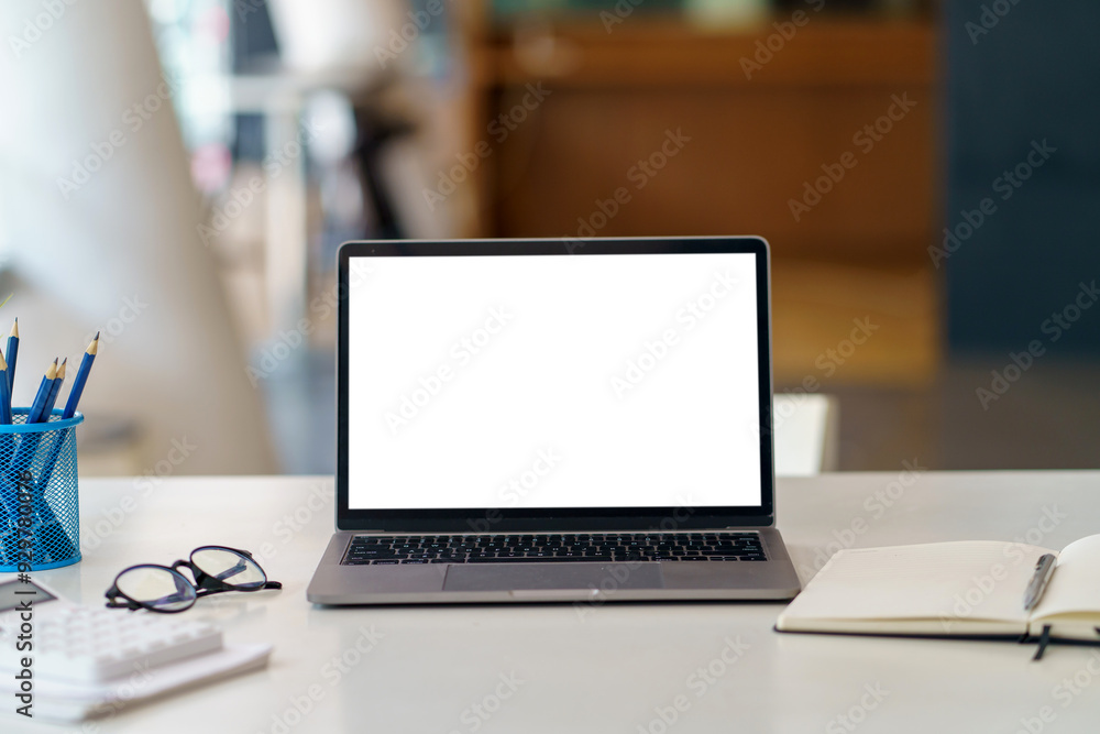 Poster workspace desk featuring an open laptop computer with a white screen, perfect for displaying your we