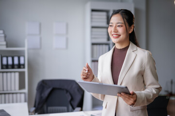 Young manager woman is holding digital tablet and smiling while working on new project in modern office