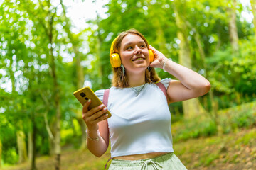 Woman listening to music standing in the forest