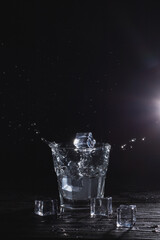 An Artistic Representation of Ice Splashing in a Glass Placed Against a Dark Background Setting