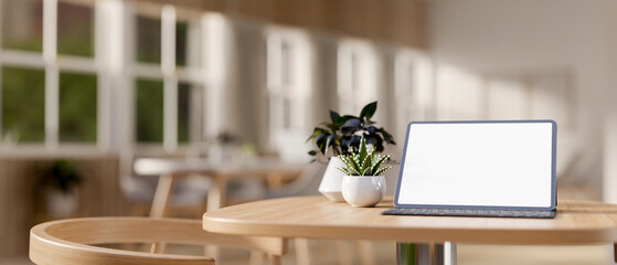 A digital tablet with a white-screen mockup on a wooden table in a cozy contemporary coffee shop.