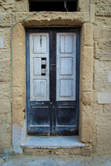 Dettaglio di una porta di legno dipinta di bianco e blu sulla facciata di un palazzo storico di Lecce, in Salento 