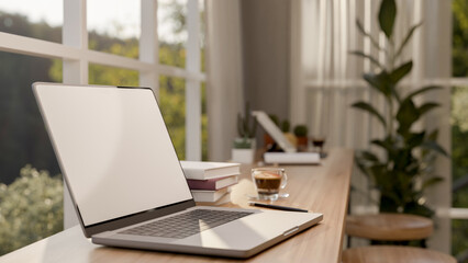 A close-up image of a laptop computer on a wooden table against the window in a minimalist cafe.