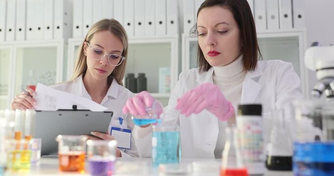 Two scientists conduct a chemical experiment with blue liquid in laboratory
