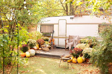Armchair near caravan trailer. Exterior RV house porch with garden furniture. Campsite with firepit...