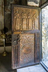 The wooden door of the church is covered with sheets of copper with embossed four saints and patterns with a cross