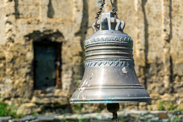 Bronze bell with beautiful carved engraving and bas-relief of grape bunches. Church wall and door...