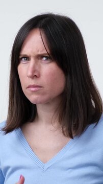 Portrait of a scared and frightened Caucasian middle aged woman, standing on white background. Concept of a horror, panic, stress. Vertical video.