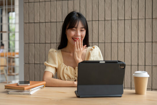 A beautiful Asian woman is talking on a video call or online meeting via her digital tablet.