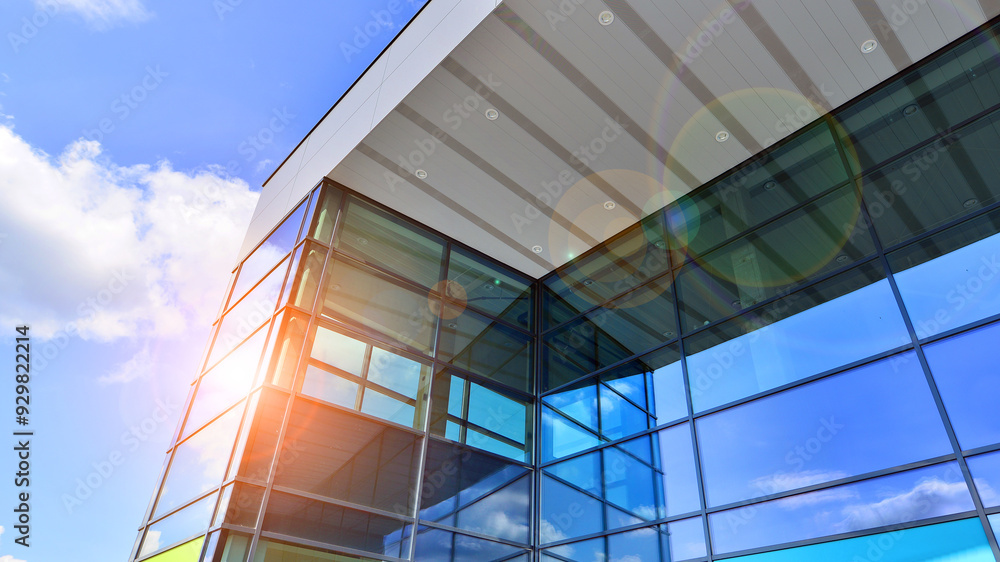 Wall mural Fragment of a modern building made of steel and glass. Abstract modern commercial architecture fragment. Walls made of shiny glass and steel under blue sky.