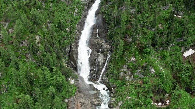 Majestic Cascate del Rutor waterfall flowing through lush green forest in the Italian Alps