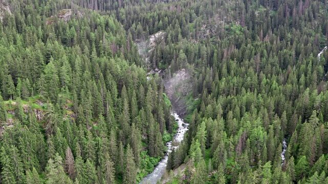 Cascate del rutor waterfall surrounded by dense forest in italy, aerial view