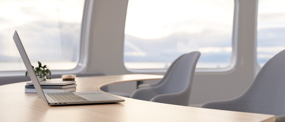 A side view of a laptop computer on a wooden curved table in a minimalist bright office.