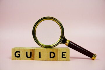 Guide with wooden blocks alphabet letters and Magnifying glass on pink background