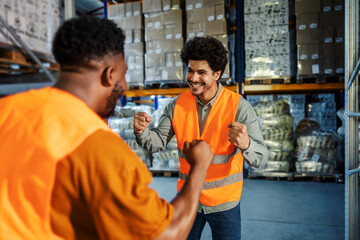 Excited cheerful multicultural storage workers celebrating winning at facility.