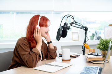 A beautiful Asian female podcaster is recording her podcast in the studio, speaking into the mic.