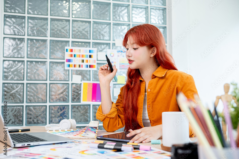 Poster a graphic designer is working in studio, focusing on selecting colors from a set of color swatches.