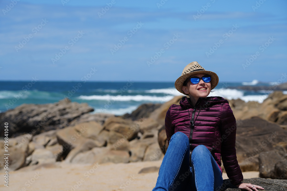 Wall mural a young woman enjoys an empty beautiful beach with sand and blue sky in porto, portugal.