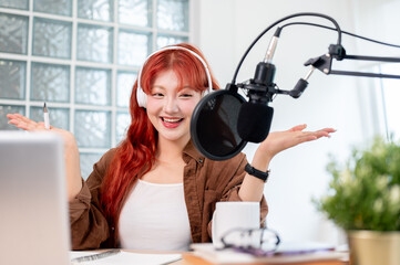 A cheerful Asian female podcaster is enjoying conducting her podcast in the studio.