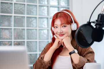 A thoughtful Asian female podcaster is listening to her guest during a remote interview.