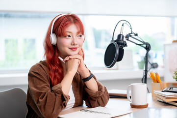 A thoughtful Asian female podcaster is listening to her guest during a remote interview.