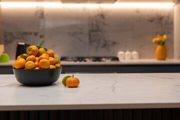 Bowl of mandarins in bowl shown in modern kitchen on counter top 
