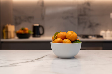 Bowl of mandarins in bowl shown in modern kitchen on counter top 