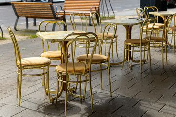 row of gold colored chairs and tables sit outside a cafe