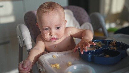 baby dirty eats. happy family a child toddler concept. baby dirty sitting messing with food at the...