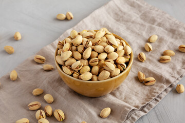 Roasted and Salted Pistachios in a Bowl on a gray background, side view.