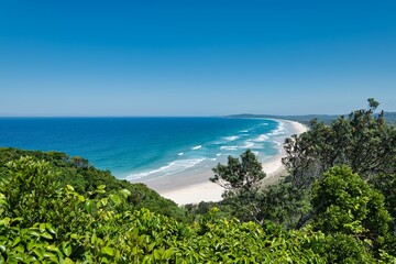'Tallow Beach' and National Park. Beautiful view from Cape Byron on a sunny day. Cloudless sky over the coastline of Byron Bay, NSW, Australia. Waves hitting the sandy beaches of New South Wales. 